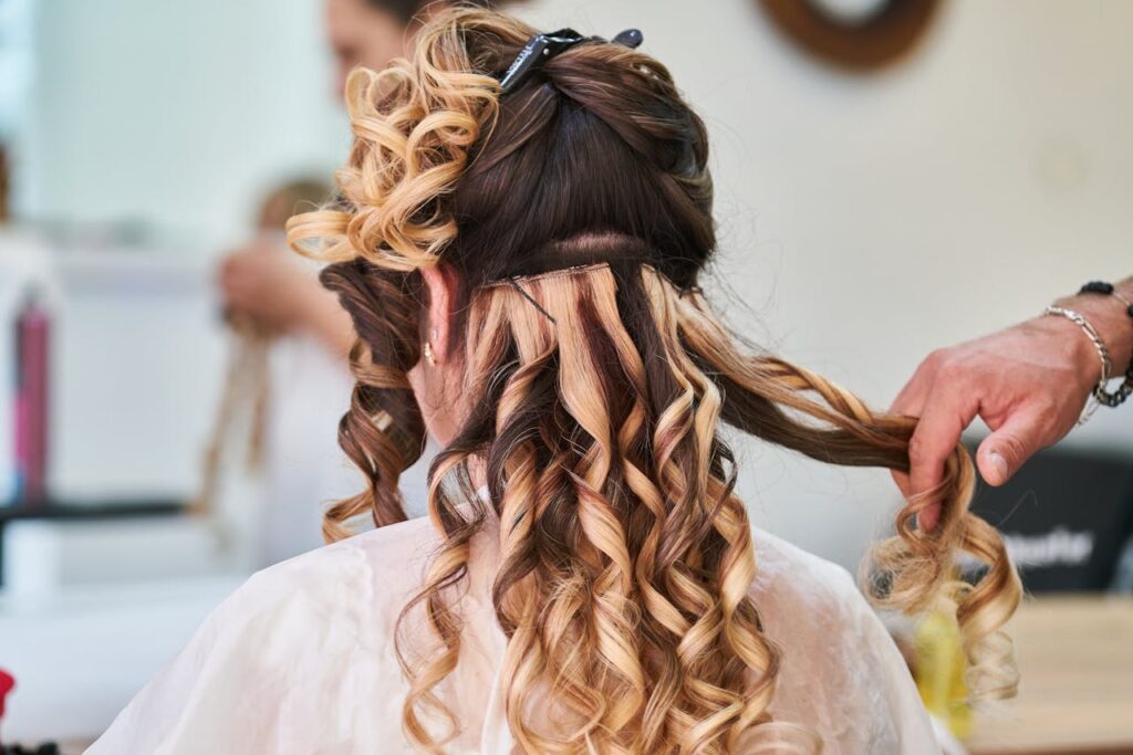 pexels-photo-3065171 Close-up of hairstylist perfecting curls on a woman's hair in a salon setting.